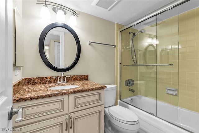 full bath featuring visible vents, toilet, vanity, and shower / bath combination with glass door