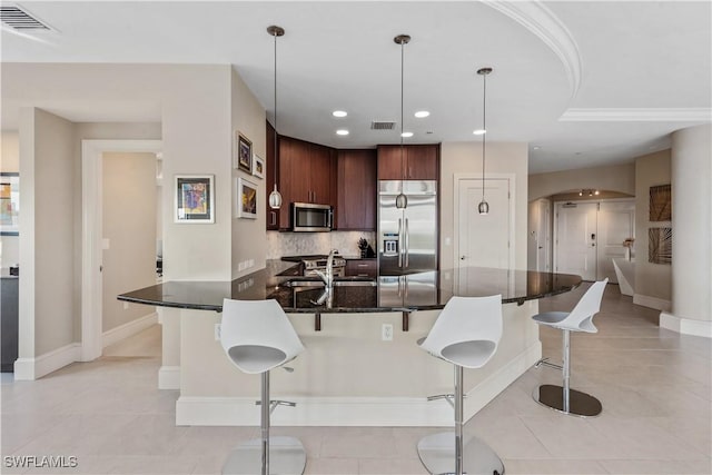 kitchen with visible vents, a breakfast bar, backsplash, arched walkways, and appliances with stainless steel finishes