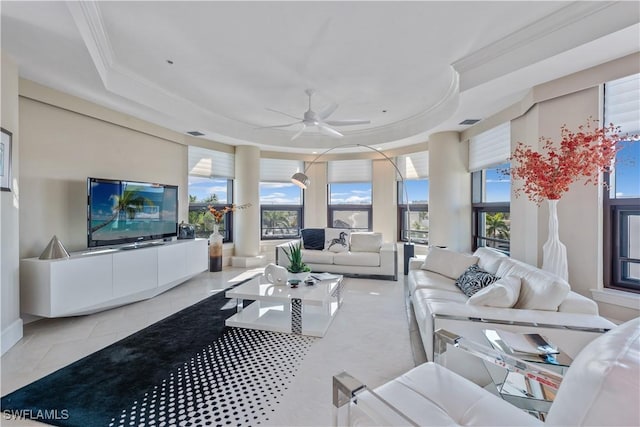 living area featuring ceiling fan, a tray ceiling, ornamental molding, and tile patterned flooring