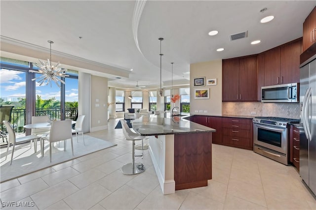 kitchen featuring visible vents, a sink, stainless steel appliances, tasteful backsplash, and open floor plan