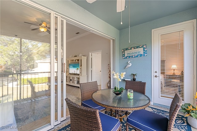 dining area featuring tile patterned floors, crown molding, a ceiling fan, and a textured wall