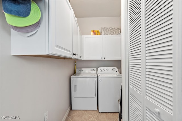 clothes washing area featuring light tile patterned flooring, cabinet space, baseboards, and washer and clothes dryer