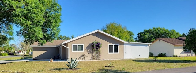 view of front of house with a carport, stucco siding, and a front yard