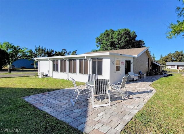 rear view of property featuring a patio area, a lawn, and stucco siding