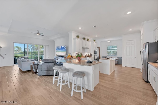 kitchen with white cabinetry, open floor plan, a center island, and freestanding refrigerator