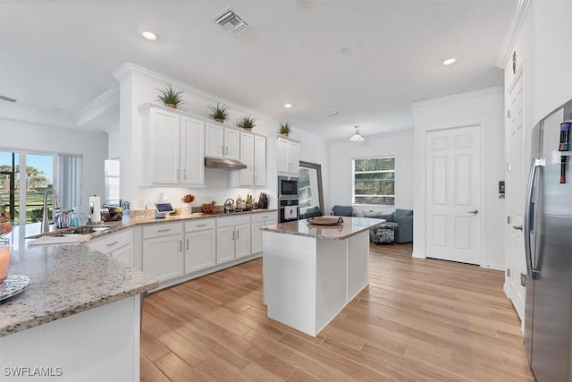 kitchen with visible vents, stainless steel appliances, a sink, white cabinets, and light wood-type flooring