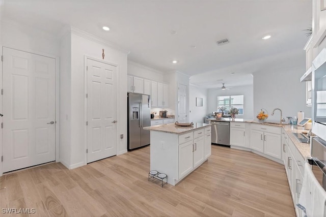 kitchen with stainless steel appliances, a peninsula, ceiling fan, and light wood finished floors