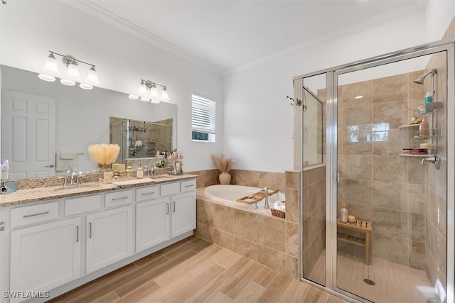 bathroom with a sink, a shower stall, a garden tub, and ornamental molding