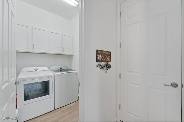 laundry room featuring cabinet space, light wood-style flooring, and separate washer and dryer