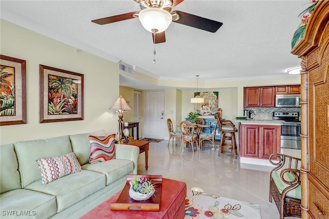 living room featuring visible vents, ornamental molding, a ceiling fan, a textured ceiling, and light tile patterned floors