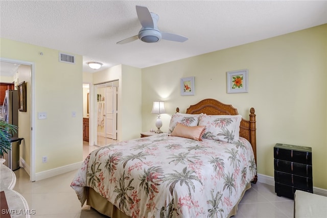 bedroom with light tile patterned floors, visible vents, a textured ceiling, and baseboards