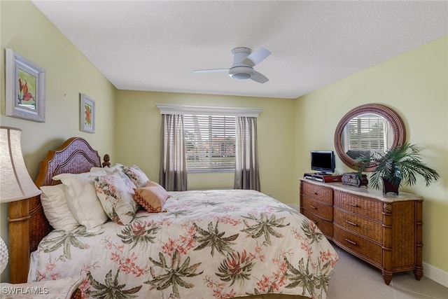 bedroom with light tile patterned floors, baseboards, a textured ceiling, and a ceiling fan