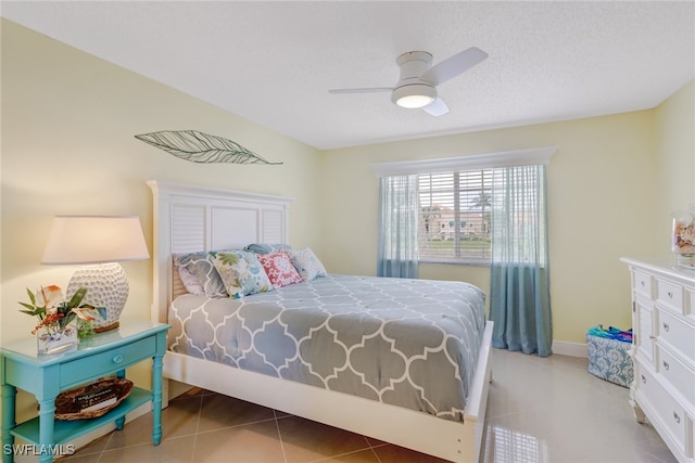 bedroom featuring tile patterned floors, baseboards, a textured ceiling, and a ceiling fan