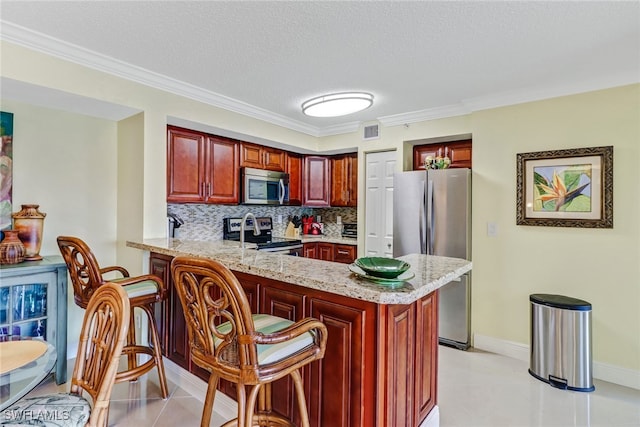 kitchen featuring backsplash, light stone countertops, a breakfast bar, appliances with stainless steel finishes, and a peninsula