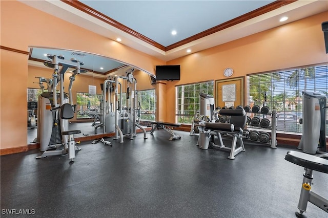 gym with a tray ceiling, recessed lighting, a high ceiling, crown molding, and baseboards