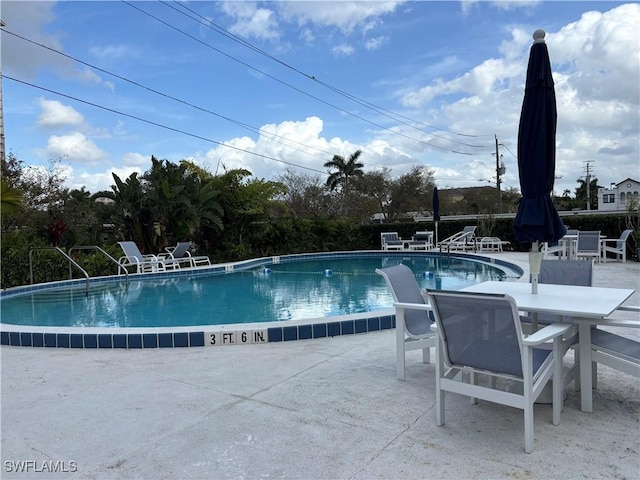 community pool with outdoor dining space and a patio area