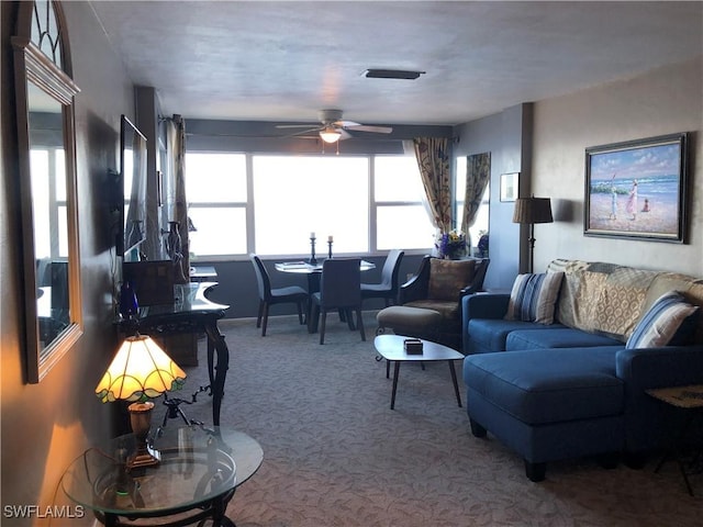 carpeted living area with visible vents and a ceiling fan