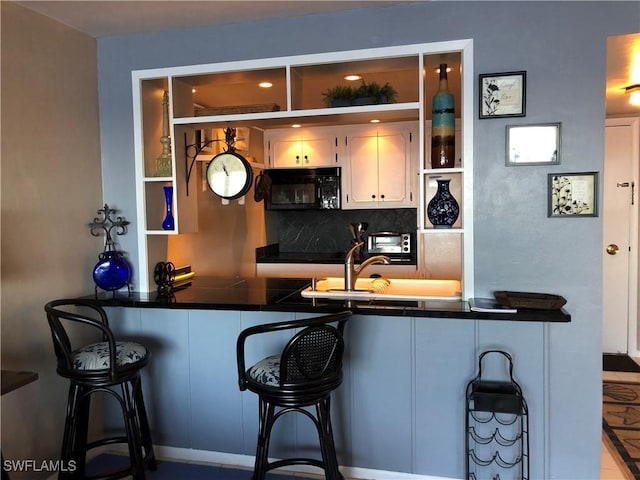 bar with wet bar, backsplash, and black microwave