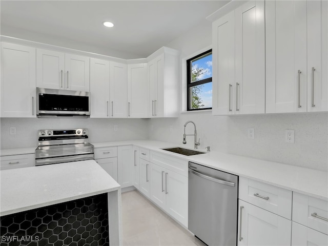 kitchen featuring decorative backsplash, recessed lighting, appliances with stainless steel finishes, white cabinets, and a sink