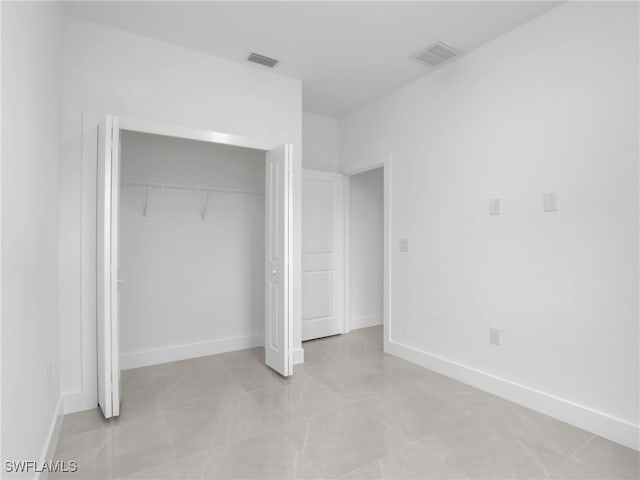 unfurnished bedroom with a closet, visible vents, and baseboards