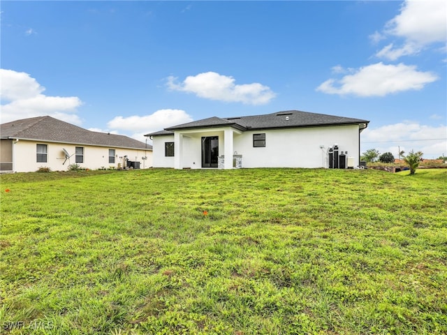 back of house featuring central AC unit, a lawn, and stucco siding