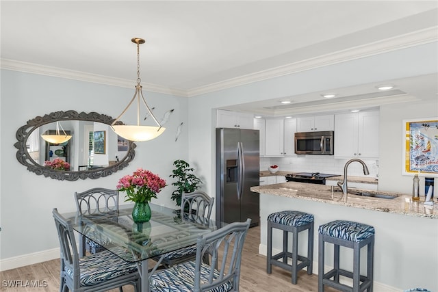 dining room featuring recessed lighting, baseboards, light wood finished floors, and ornamental molding