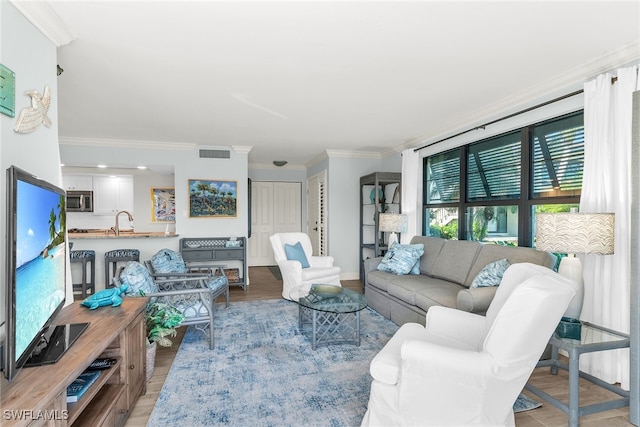 living area featuring visible vents, ornamental molding, and light wood finished floors