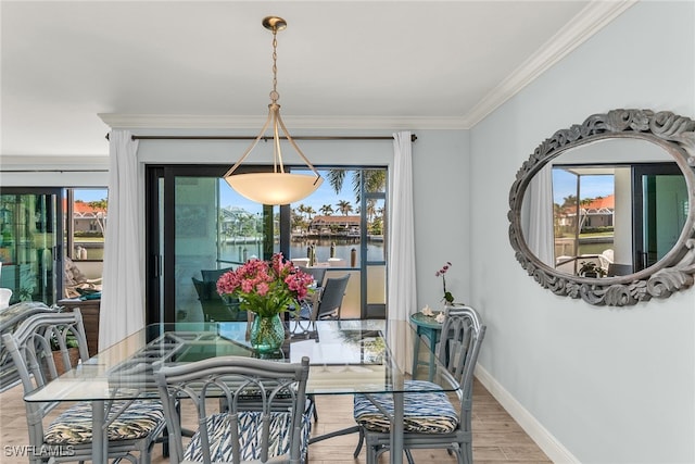 dining room featuring baseboards, crown molding, and light wood finished floors