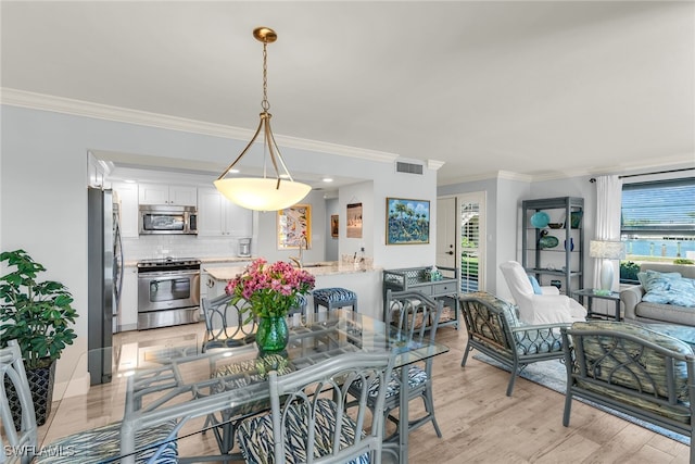 dining space featuring visible vents, light wood-style floors, and crown molding