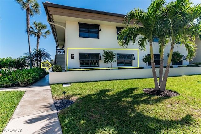 view of front of home featuring stucco siding and a front yard