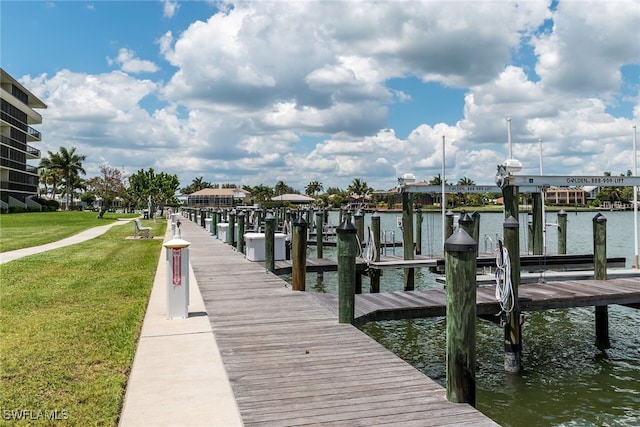 view of dock featuring a water view, boat lift, and a lawn