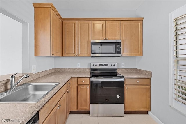 kitchen featuring light tile patterned flooring, appliances with stainless steel finishes, light countertops, and a sink