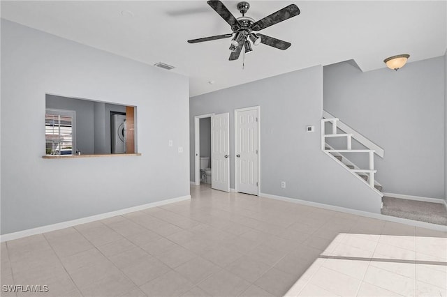 interior space featuring tile patterned flooring, visible vents, baseboards, stairway, and a ceiling fan