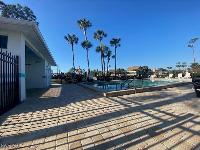 pool with a patio area and fence