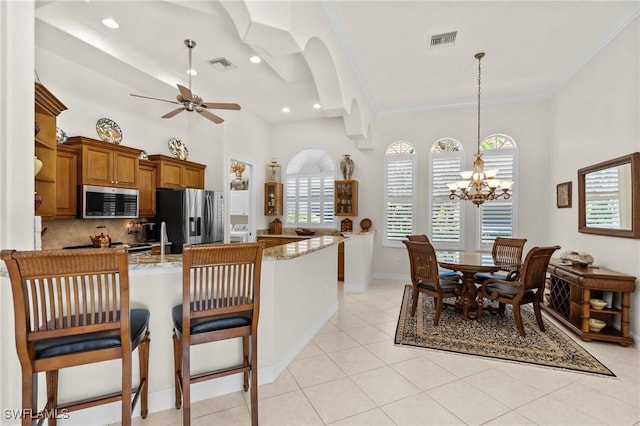 2874 Lone Pine Ln, Naples, FL 34119 - kitchen featuring visible vents, brown cabinetry, appliances with stainless steel finishes, and ceiling fan with notable chandelier