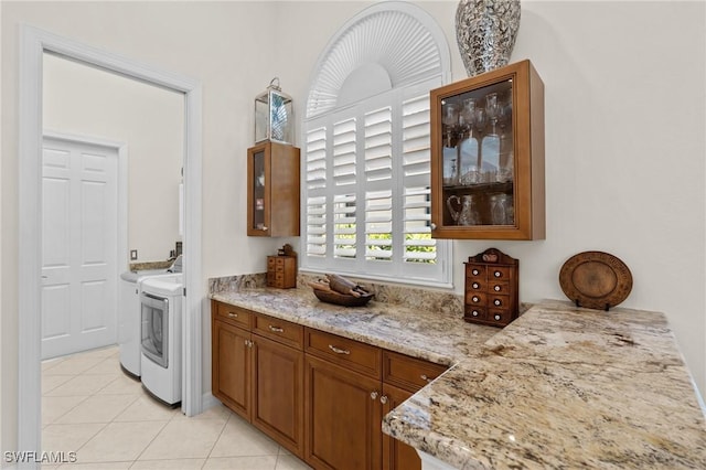 2874 Lone Pine Ln, Naples, FL 34119 - kitchen with brown cabinets, light stone countertops, light tile patterned floors, washing machine and dryer, and glass insert cabinets
