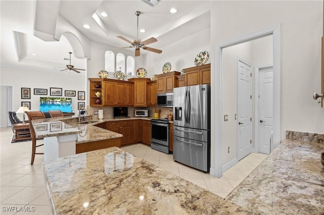 2874 Lone Pine Ln, Naples, FL 34119 - kitchen with brown cabinetry, a peninsula, ceiling fan, a sink, and appliances with stainless steel finishes