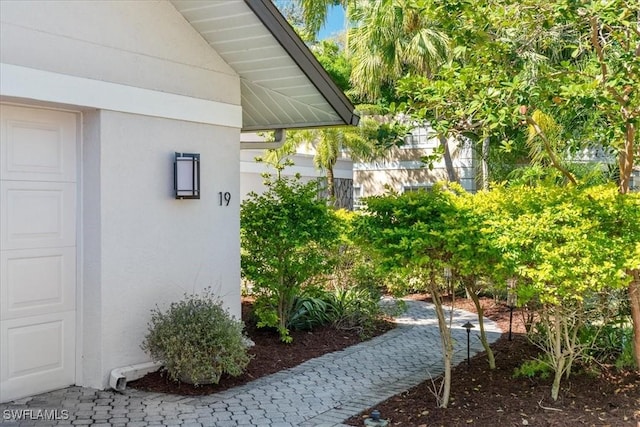 view of side of home featuring stucco siding and a garage