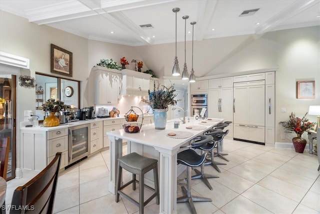 kitchen with light countertops, wine cooler, beamed ceiling, and visible vents