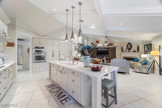 kitchen with light tile patterned floors, stainless steel double oven, white cabinets, and a sink