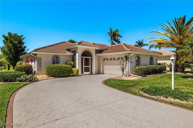 mediterranean / spanish house with a tile roof, stucco siding, concrete driveway, and a garage