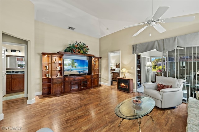 living room with visible vents, a fireplace, wood finished floors, high vaulted ceiling, and a ceiling fan