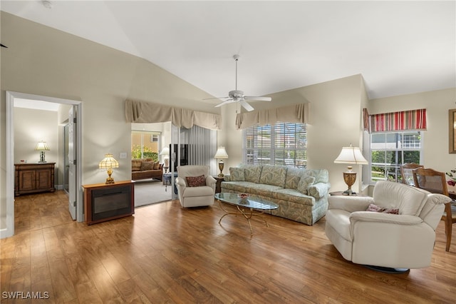 living room featuring a ceiling fan, lofted ceiling, wood finished floors, and a healthy amount of sunlight