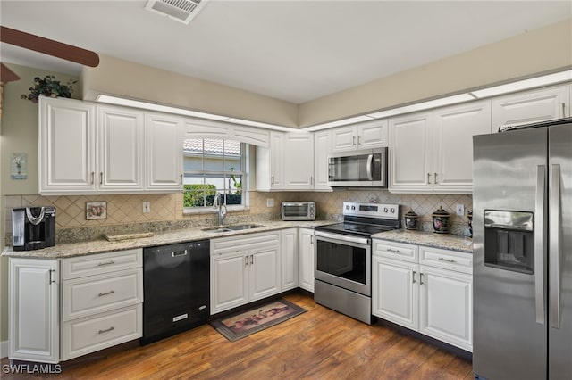 kitchen with visible vents, a sink, dark wood finished floors, stainless steel appliances, and white cabinets