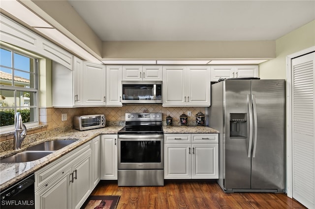 kitchen with a sink, stainless steel appliances, backsplash, and white cabinetry