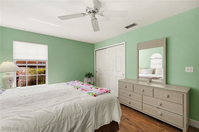 bedroom with visible vents, a closet, dark wood-style floors, and a ceiling fan