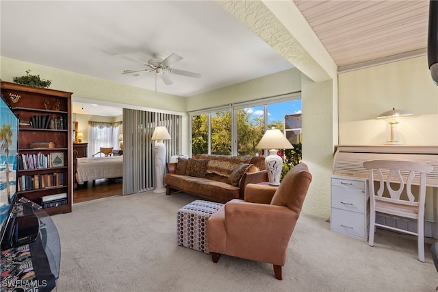 carpeted living area featuring plenty of natural light, a ceiling fan, and a textured wall