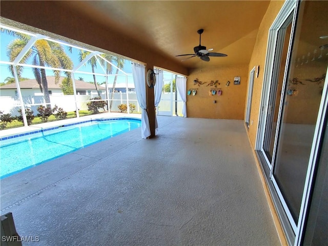 view of swimming pool with a fenced in pool, ceiling fan, fence, glass enclosure, and a patio area