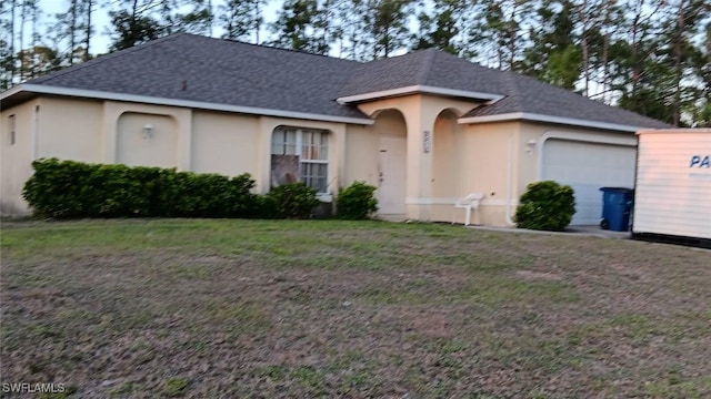 ranch-style house with a garage, stucco siding, a front yard, and roof with shingles