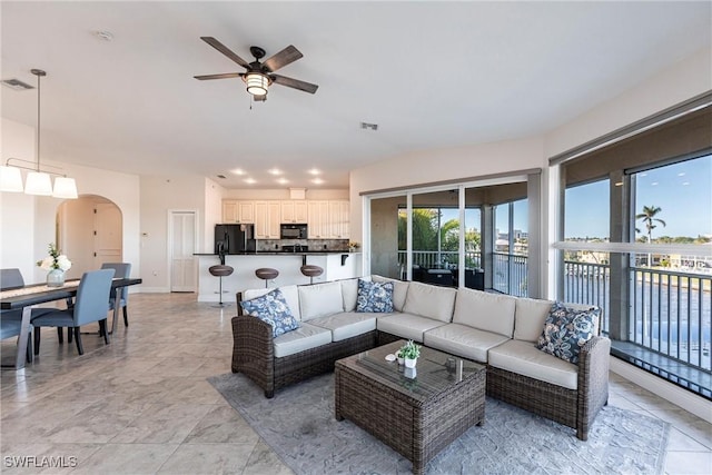 living room featuring visible vents, arched walkways, baseboards, and ceiling fan